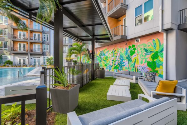 Arte St. Pete apartments pool area with plush seating and colorful mural.