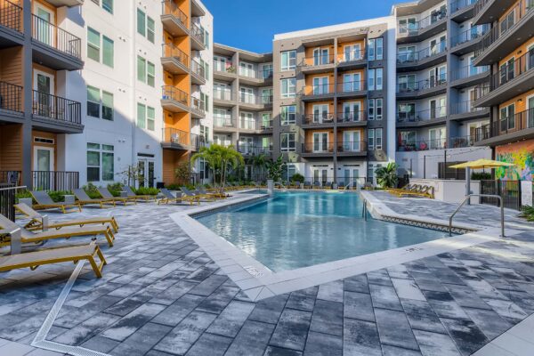 Arte St. Pete apartments pool area with lounge chairs and palm trees.