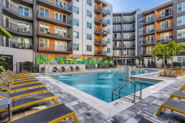 Arte St. Pete apartments pool area with lounge chairs and palm trees.