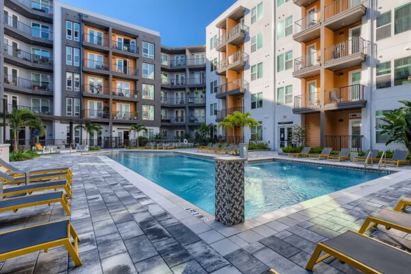 Arte St. Pete apartments pool area with lounge chairs and palm trees.