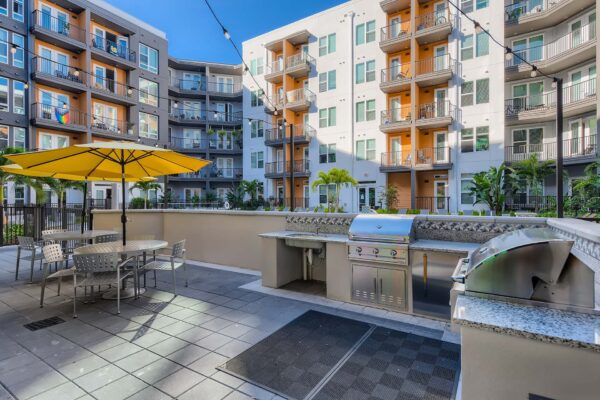 Arte St. Pete apartments pool area with BBQ grills and dining tables.