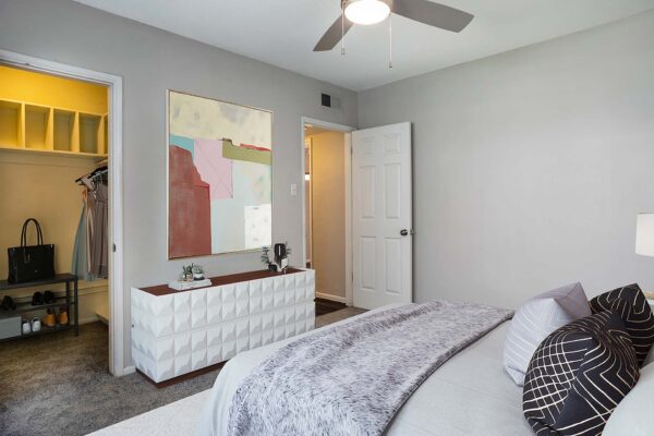 Aura at Midtown apartment bedroom with plush bed, modern dresser, and large artwork.