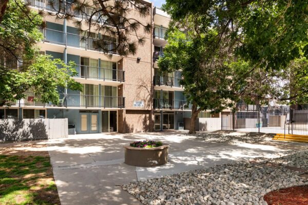 Beacon House apartments courtyard with lush planters and tall trees.