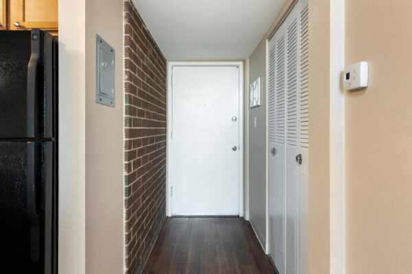 Beacon House apartment hallway with brick accent wall and closet.