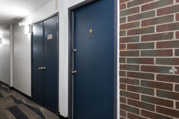 Beacon House apartments hallway with brick accent wall and blue apartment doors.