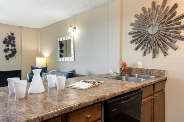 Beacon House apartment kitchen with wood cabinets, tan counters, and stainless steel sink.