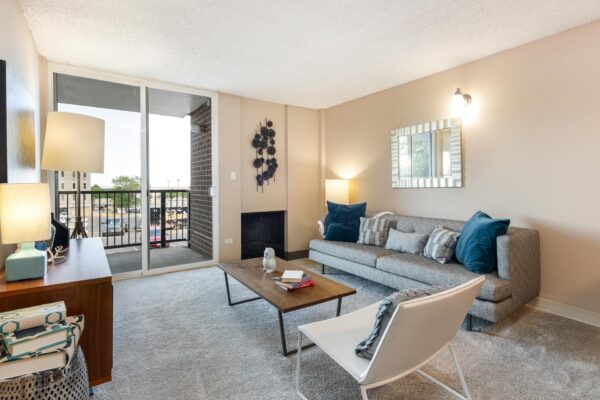 Beacon House apartment living room with plush carpet, fireplace, modern furniture, and balcony door.