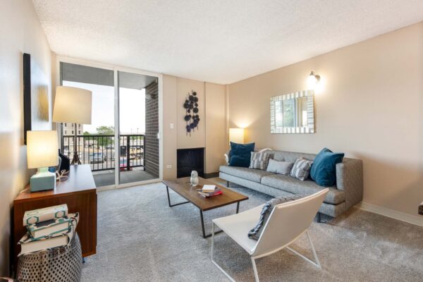 Beacon House apartment living room with plush carpet, fireplace, modern furniture, and balcony door.