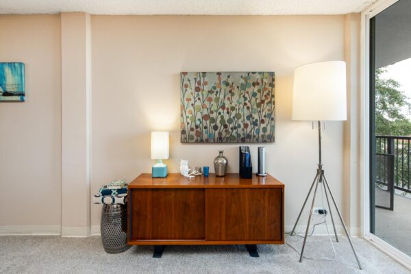 Beacon House apartment living room with plush carpet, wood console, large lamp, and artwork.