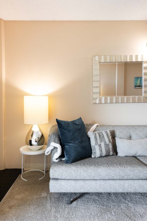 Beacon House apartment living room with plush carpet, lamp, and couch.