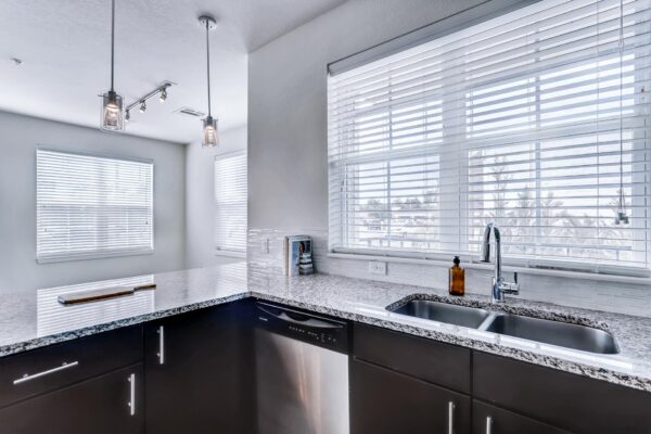 Centre Court apartment kitchen with wood cabinets, stone counters, and stainless steel sink.