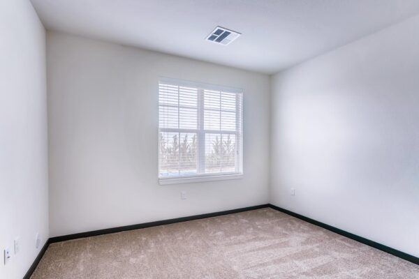 Centre Court apartment bedroom with plush carpet and large window.