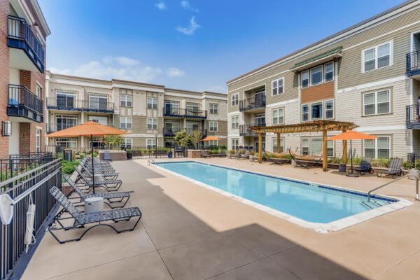 Centre Court apartments pool area with lounge chairs, umbrellas, and pergola.