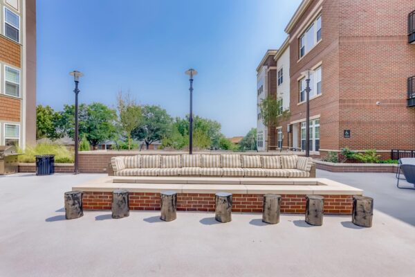 Centre Court apartments outdoor lounge with plush couch, metal stools, and fire pit.