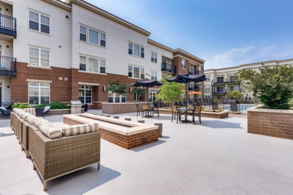 Centre Court apartments outdoor lounge with plush seating, fire pit, and dining tables with umbrellas.
