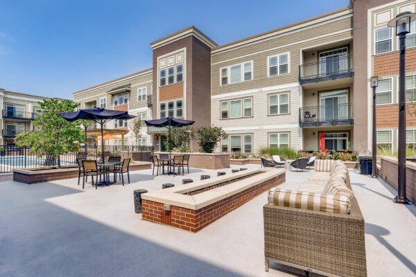 Centre Court apartments outdoor lounge with plush seating, fire pit, and dining tables with umbrellas.