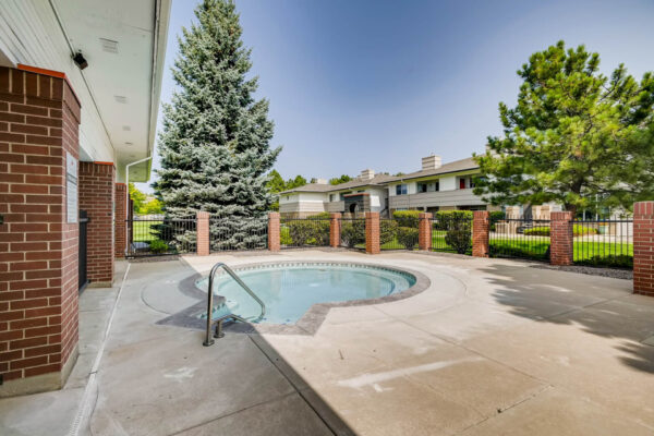 Copper Ridge apartments pool area with hot tub and tall pine trees.