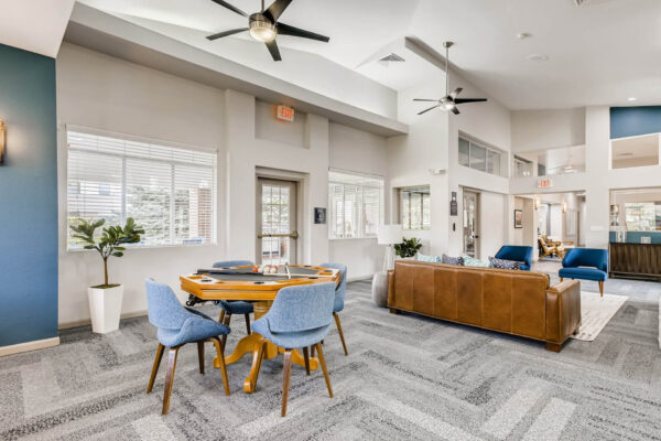 Copper Ridge apartments clubroom with plush seating, games table, and large windows.