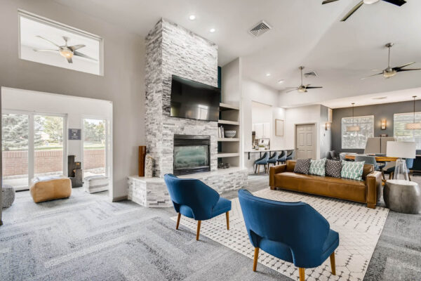 Copper Ridge apartments clubroom with plush seating, fireplace, TV, and large windows.