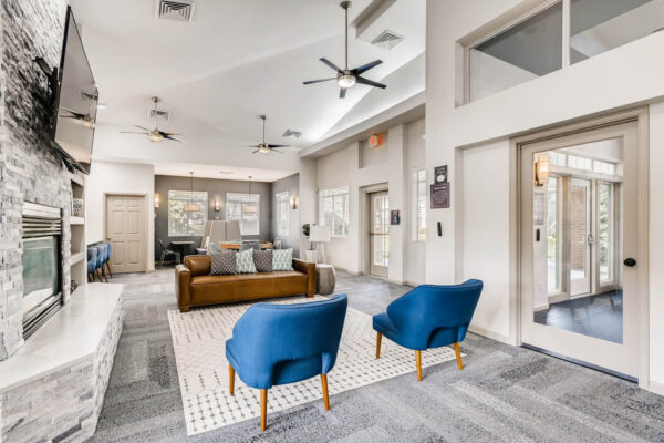 Copper Ridge apartments clubroom with plush seating, fireplace, TV, and large windows.