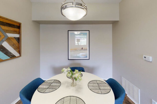 Copper Ridge apartment dining room with dining table, modern light fixture, and artwork.