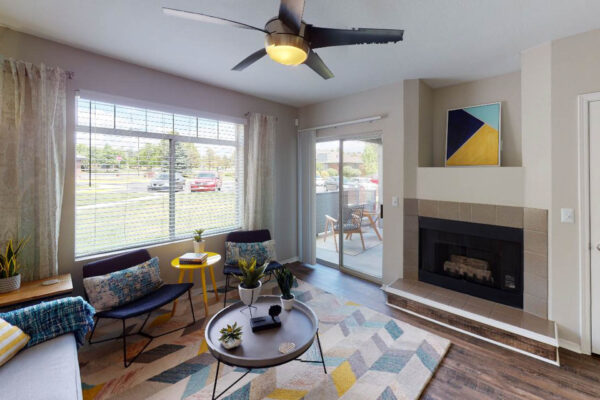 Copper Ridge apartment living room with wood style floor, fireplace, large windows, and balcony door.