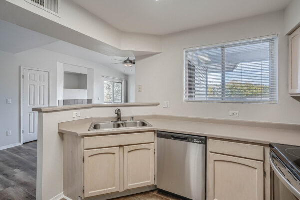 Copper Ridge apartment kitchen with tan cabinets and counters and stainless steel and dishwasher.
