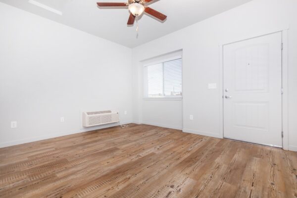 Cottages at Jet Wing apartment living room with wood style floors, ceiling fan, and large windows.