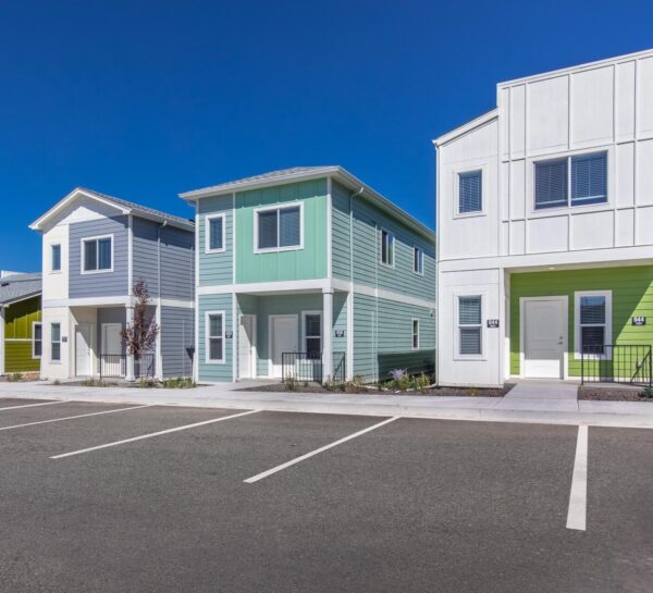 Cottages at Jet Wing apartments with ample parking, rocky landscaping, and colorful accent paint.