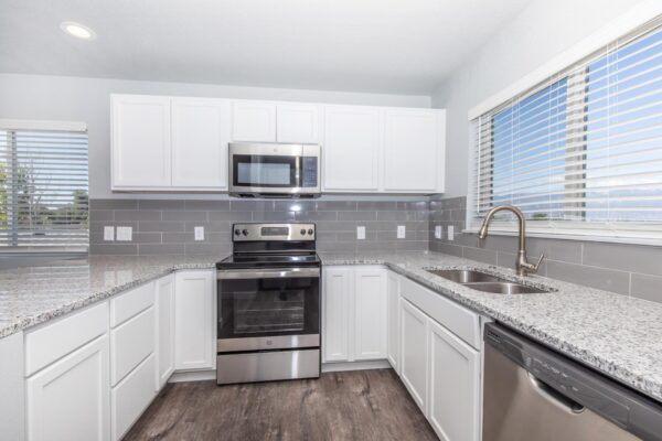 Cottages at Torin Point apartment kitchen with wood style floor, white cabinets, and stainless steel appliances.