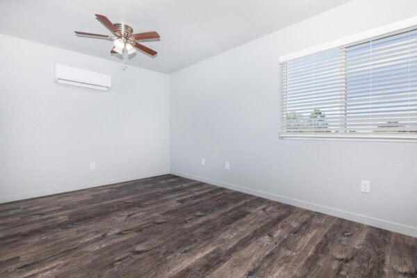 Cottages at Torin Point apartment living room with wood style floor, large window, and ceiling fan.