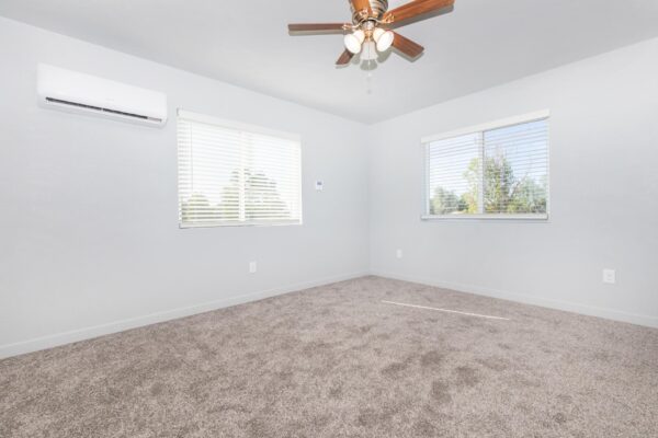 Cottages at Torin Point apartment bedroom with plush carpet, large windows, and ceiling fan.