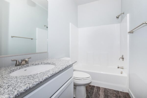 Cottages at Torin Point apartment kitchen with wood style floor, white cabinet, granite counter, and shower tub.