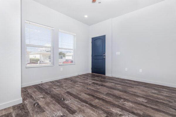 Cottages at Torin Point apartment living area with wood style floor, blue door, and large windows.