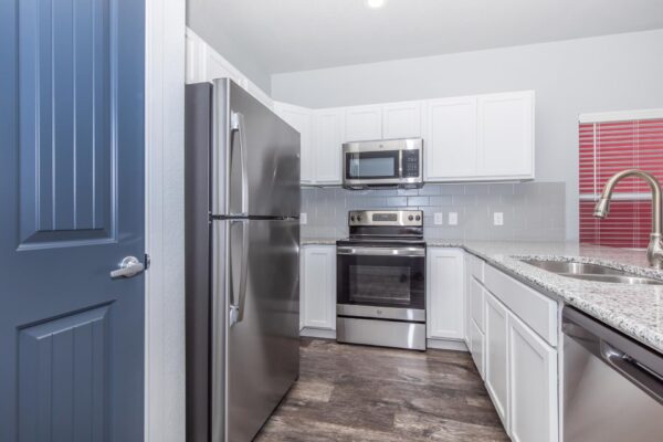 Cottages at Torin Point apartment kitchen with wood style floor, white cabinets, and stainless steel appliances.