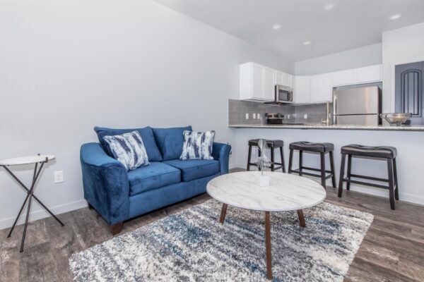 Cottages at Torin Point apartment living area with wood style floor, plush couch, and breakfast bar with stools.