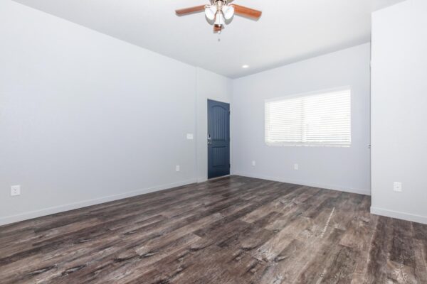 Cottages at Torin Point apartment living area with wood style floor, large windows, and ceiling fan.