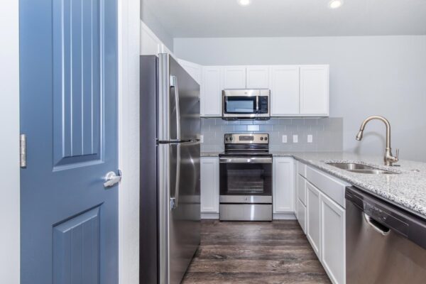 Cottages at Torin Point apartment kitchen with wood style floor, white cabinets, granite counters, and stainless steel appliances.