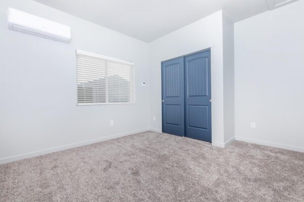 Cottages at Torin Point apartment bedroom with plush carpet, blue doors, and large windows.