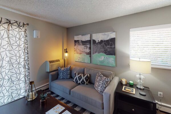 Flats at Pinecliff apartment living room with plush seating, large artwork, and large windows.
