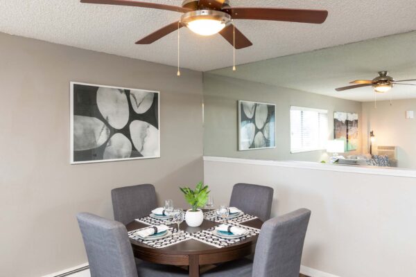 Flats at Pinecliff apartment dining room with dining table, large mirror, artwork, and ceiling fan.