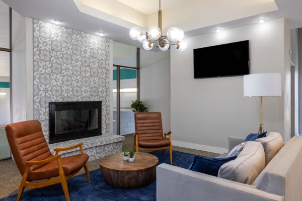 Flats at Pinecliff apartment lounge with plush seating, fireplace, TV, and modern light fixture.