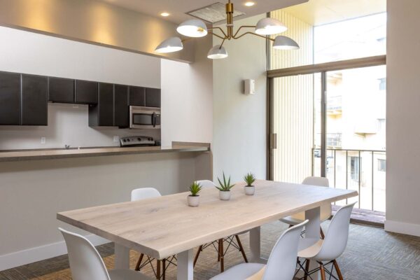 Flats at Pinecliff apartments community kitchen with dining table, balcony door, and brass light fixture.