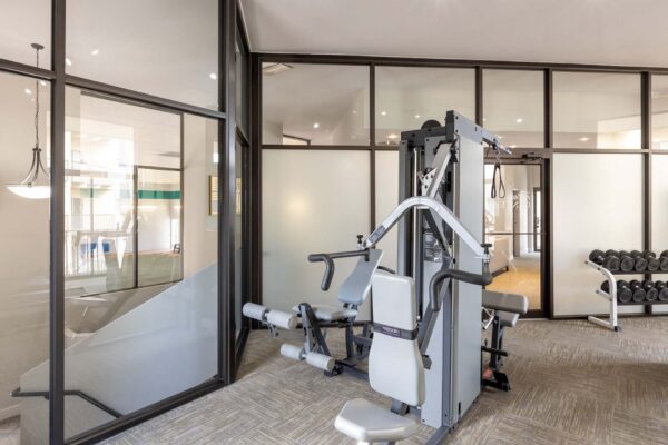 Flats at Pinecliff apartments fitness center with weightlifting equipment.