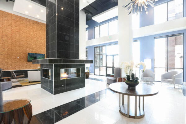 Forum Fitzsimons apartments clubroom with plush seating, fireplace, and large windows.