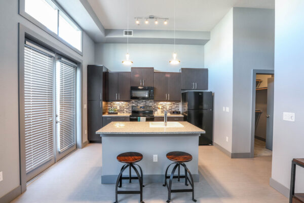 Forum Fitzsimons apartment kitchen with dark cabinets, light counters, and black appliances.