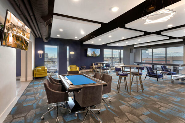 Forum Fitzsimons apartments lounge with poker table, TV, and bar tables.