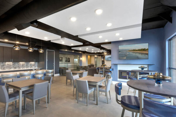 Forum Fitzsimons apartments lounge with dining tables and fireplace.