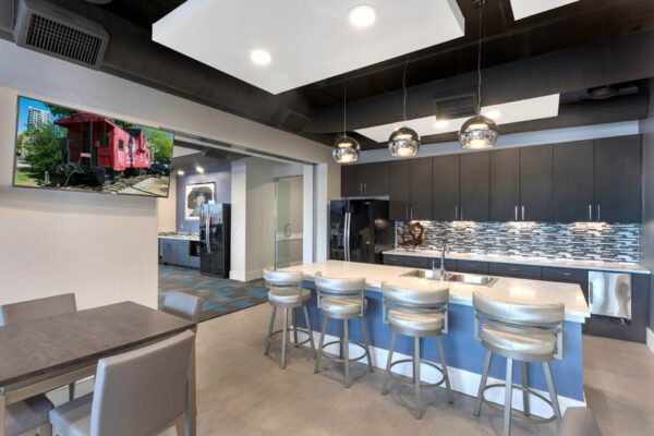 Forum Fitzsimons apartments community kitchen with barstools and TV.