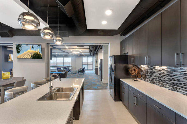 Forum Fitzsimons apartments community kitchen with bar stools and TV.